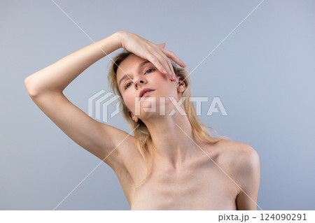 Ethereal Beauty: A Striking Portrait of a Woman with Graceful Poise and Enigmatic Expression Against a Soft Gray Background 124090291