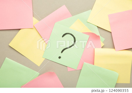 Question marks on colour stickers on grey background. Top view. 124090355