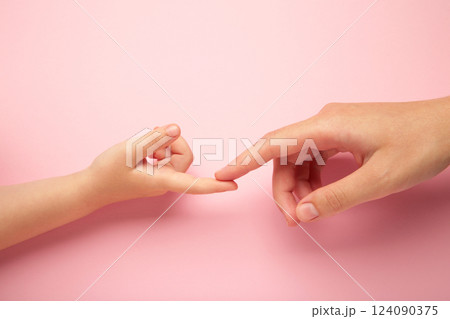 Mother holding daughter hand on pink background. 124090375