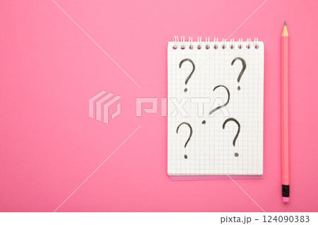 Question mark symbol on white paper with pencil on pink background 124090383