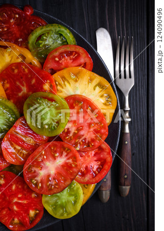 Sliced multi-colored tomatoes on black plate 124090496