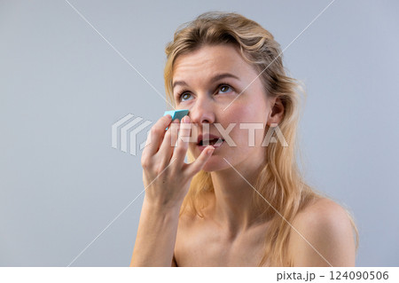 Beauty Routine: A Woman Applying Makeup with a Cosmetic Sponge in a Studio Environment Beauty Routine: A Woman Applying Makeup with a Cosmetic Sponge in a Studio Environment 124090506