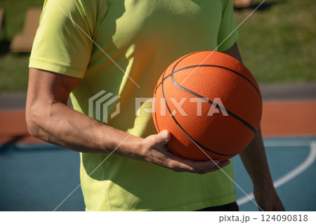 Basketball player, man holding orange ball on sports court. Sports goals competition game, champion outdoor workout. Close up. Copy space 124090818