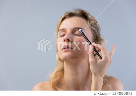 A Close-Up Portrait of a Woman Applying Makeup with Precision: Embracing Beauty and Confidence in Every Stroke of the Brush 124090872