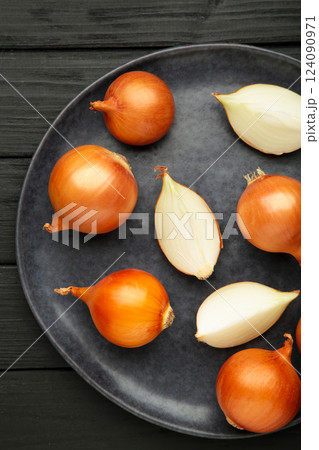 Sliced yellow onions on plate on black background. Vertical photo 124090971