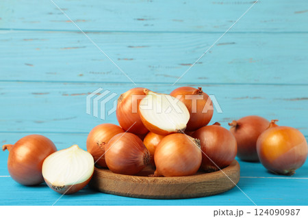 Fresh healthy onions and sliced onion on wooden board on blue background. 124090987
