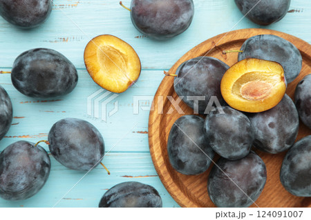 Fresh plums on wooden plate on blue wooden background 124091007
