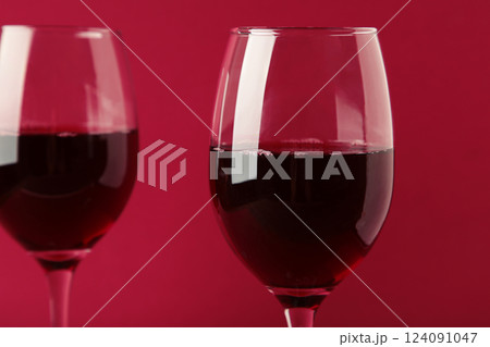 Dark studio shot of glasses of red wine on dark red background. Space for text Dark studio shot of glasses of red wine on dark red background. Space for text 124091047