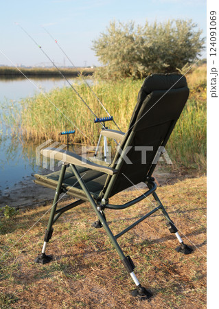 Fisherman's chair and fishing rods in the background over the river at sunrise, foggy morning. Fishing concept. Vertical photo Fisherman's chair and fishing rods in the background over the river at sunrise, foggy morning. Fishing concept. Vertical photo 124091069