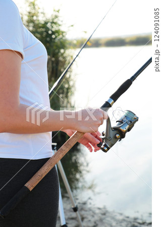 Close-up of a woman holding a fishing rod with a reel, sport fishing Close-up of a woman holding a fishing rod with a reel, sport fishing 124091085