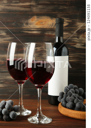 Wine bottle and wine glass with grapes on brown wooden background. Vertical photo Wine bottle and wine glass with grapes on brown wooden background. Vertical photo 124091138