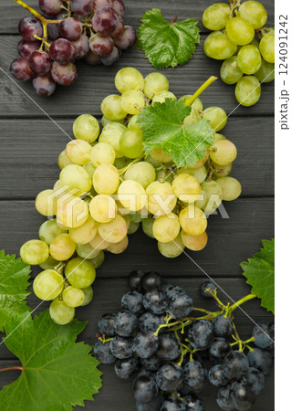 Assortment of different grapes on black wooden background. Vertical photo Assortment of different grapes on black wooden background. Vertical photo 124091242
