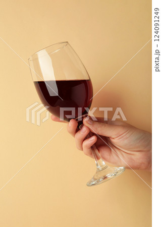 Young girl holding glass of tasty red wine on beige background. Vertical photo Young girl holding glass of tasty red wine on beige background. Vertical photo 124091249