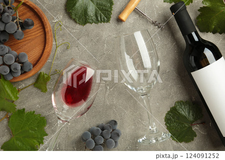 Wine bottle and wine glass with grapes on grey concrete background. 124091252