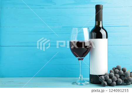 Wine bottle and wine glass with grapes on blue wooden background. Space for text Wine bottle and wine glass with grapes on blue wooden background. Space for text 124091255