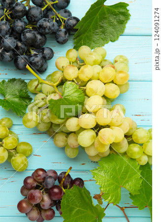 Assortment of different grapes on blue wooden background. Vertical photo 124091274