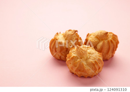 Homemade profiteroles with cream on pink background. Fresh baked golden profiterole. Homemade profiteroles with cream on pink background. Fresh baked golden profiterole. 124091310