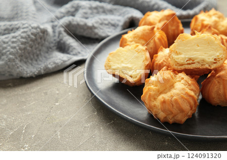 Homemade profiteroles with cream on plate on grey background. Fresh baked golden profiterole. 124091320