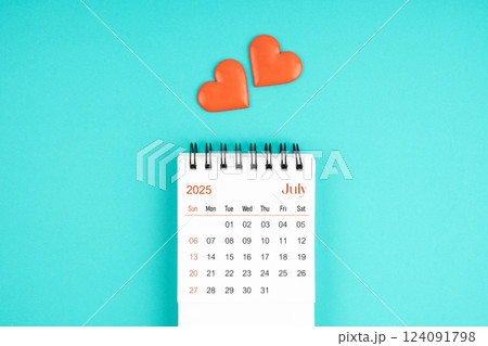 July 2025 desk calendar with red heart on blue background. 124091798