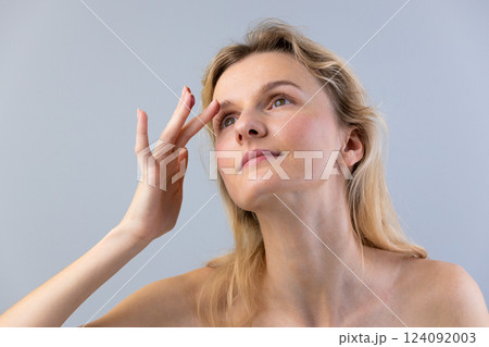 A Thoughtful Woman with Natural Beauty Reflecting on Life Experiences and Expressing Inner Thoughts and Emotions Against a Soft Gray Background 124092003