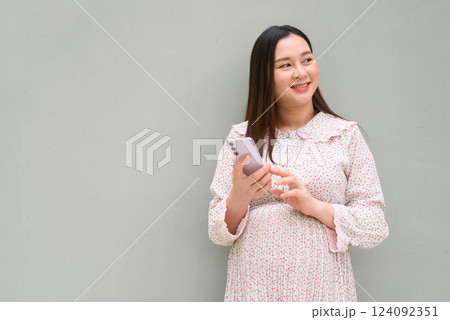 Pregnant woman portrait against plain wall 124092351