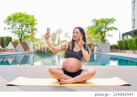 Pregnant woman doing yoga next to swimming pool Pregnant woman doing yoga next to swimming pool 124092447