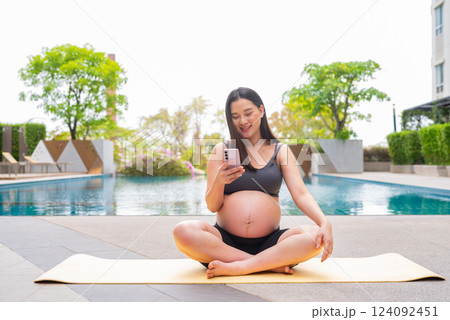 Pregnant woman doing yoga next to swimming pool 124092451