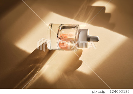 A bottle of luxury serum with petals on a beige background with daffodils. A bottle of luxury serum with petals on a beige background with daffodils. 124093183