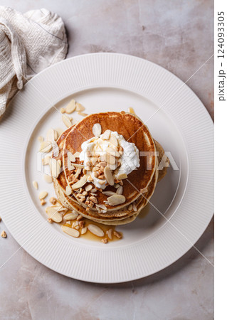 Stack of vegan pancakes with cream, syrup and nuts. 124093305