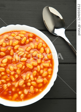 White beans in tomato sauce in white bowl on black background. 124093812