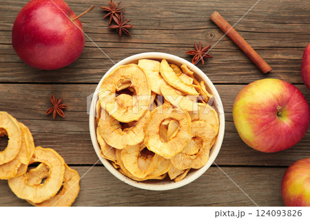Dried apple chips with cinnamon and star anise with fresh apple. Homemade dried organic apple sliced on grey background. Dried apple chips with cinnamon and star anise with fresh apple. Homemade dried organic apple sliced on grey background. 124093826
