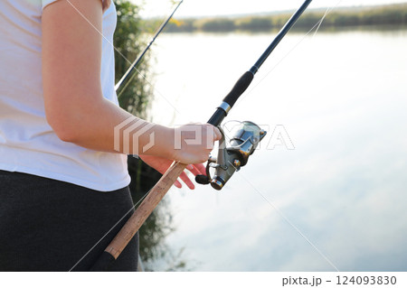 Close-up of a woman holding a fishing rod with a reel, sport fishing Close-up of a woman holding a fishing rod with a reel, sport fishing 124093830