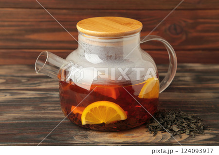 Black tea with lemon in glass teapot on brown background. Healthy drink concept. 124093917