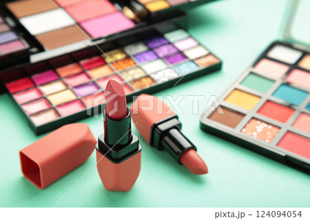 Colorful lipsticks and palette shadow on mint background. Makeup 124094054