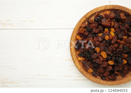 Raisins in wooden bowl on white background. Raisins in wooden bowl on white background. 124094055