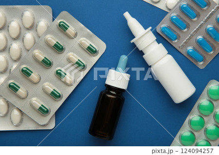 Nasal spray with pills on blue background. Top view Nasal spray with pills on blue background. Top view 124094257