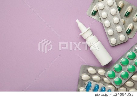 Nasal spray with pills on purple background. Top view Nasal spray with pills on purple background. Top view 124094353