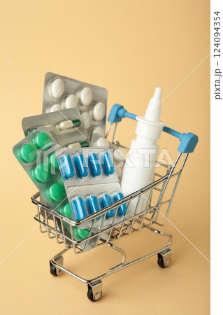 Shopping cart loaded with pills on beige background. The concept of medicine and the sale of drugs. Vertical photo Shopping cart loaded with pills on beige background. The concept of medicine and the sale of drugs. Vertical photo 124094354
