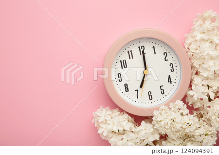 Clock alarm and lilac flowers on pink background. Environment concept. spring season. copy space. Clock alarm and lilac flowers on pink background. Environment concept. spring season. copy space. 124094391