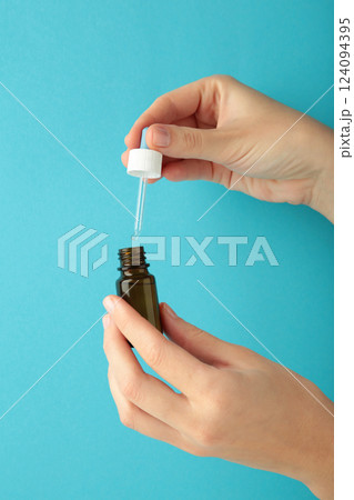 Nasal drops in hand on blue background. Runny nose treatment concept. Vertical photo 124094395