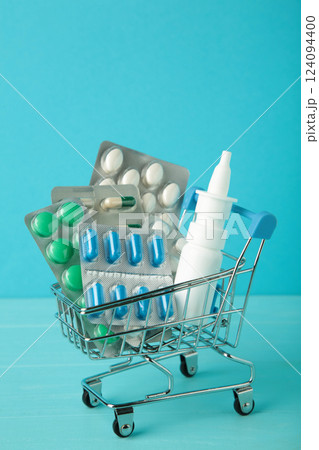 Shopping cart loaded with pills on blue background. The concept of medicine and the sale of drugs. Vertical photo Shopping cart loaded with pills on blue background. The concept of medicine and the sale of drugs. Vertical photo 124094400