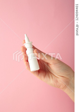 Hand holds a bottle of nasal drops on pink background. Vertical photo Hand holds a bottle of nasal drops on pink background. Vertical photo 124094401