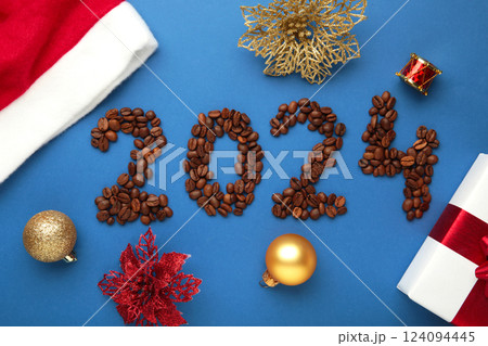 The inscription number 2024 laid out from coffee beans with Christmas decoration. Happy New Year 2024 on blue background. The inscription number 2024 laid out from coffee beans with Christmas decoration. Happy New Year 2024 on blue background. 124094445