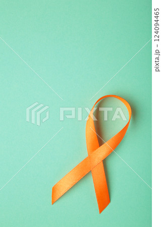 Orange ribbon on mint background . Healthcare and medicine concept. Multiple Sclerosis awareness. Leukemia awareness. Empty text space. Vertical photo Orange ribbon on mint background . Healthcare and medicine concept. Multiple Sclerosis awareness. Leukemia awareness. Empty text space. Vertical photo 124094465