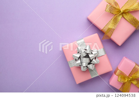 Pink gift boxes with silver and gold bow on purlpe background. 124094538