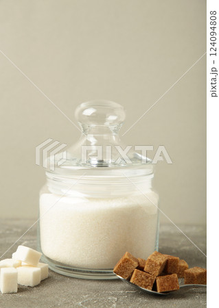 Jar with white sugar on grey background. Space for text. Vertical photo Jar with white sugar on grey background. Space for text. Vertical photo 124094808