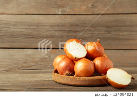 Fresh healthy onions and sliced onion on wooden board on grey wooden background. Fresh healthy onions and sliced onion on wooden board on grey wooden background. 124094821
