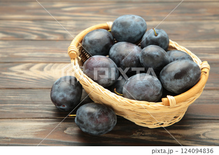 Basket of fresh ripe plums on brown wooden background Basket of fresh ripe plums on brown wooden background 124094836