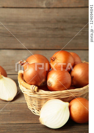 Fresh healthy onions and sliced onion on basket on grey wooden background. Vertical photo Fresh healthy onions and sliced onion on basket on grey wooden background. Vertical photo 124094841
