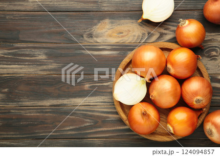 Fresh healthy onions and sliced onion on wooden board on brown wooden background. Fresh healthy onions and sliced onion on wooden board on brown wooden background. 124094857